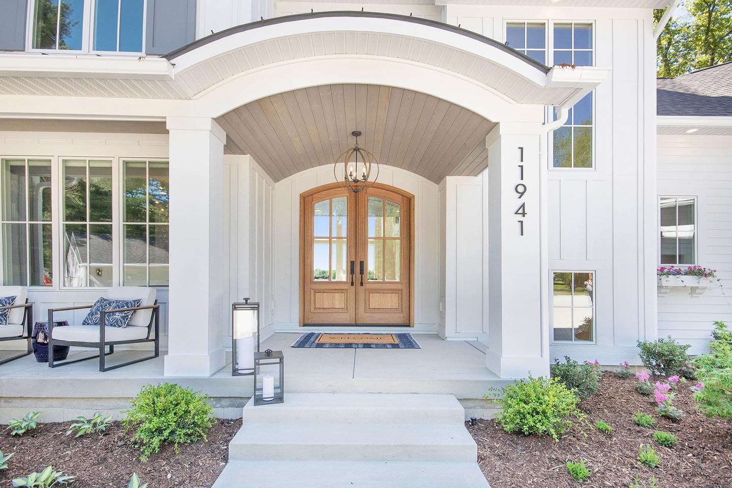 Wood Double Doors Create Warm Contrast On Elegant Home Natural wood entry doors situated under large overhang on elegant home