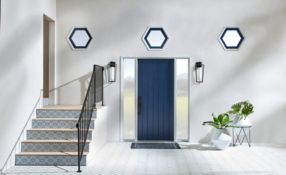 Custom Hexagon Windows Featured In Unique Entryway Design gray entryway with navy front door, mosaic tile steps, and three hexagon shape windows above the doorway