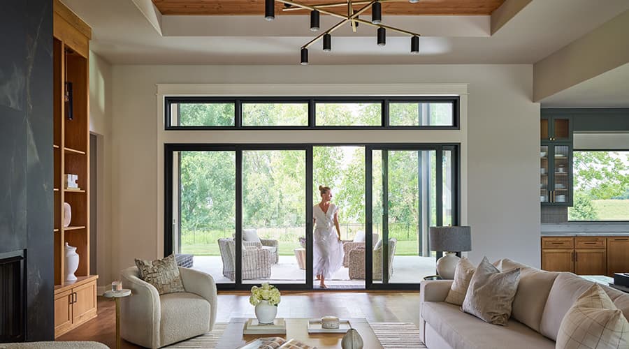 Modern living room with neutral furniture and large sliding glass doors opening to a patio.