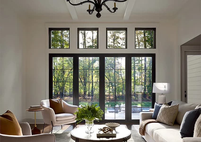 A bright living room with large black-frame windows maximizing natural light for energy efficiency.
