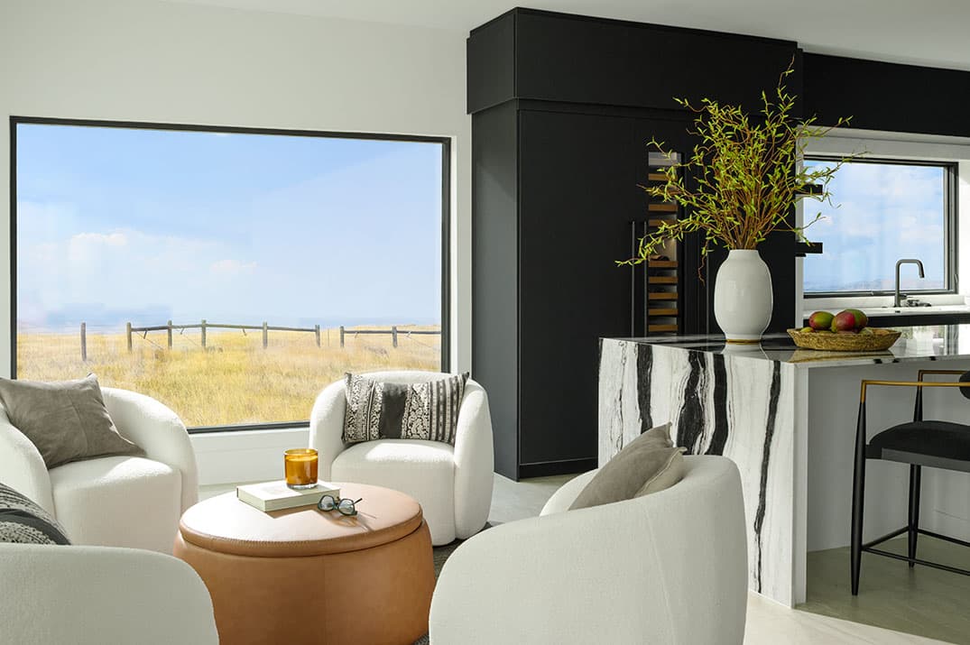 A bright living room with large black-frame windows maximizing natural light for energy efficiency.