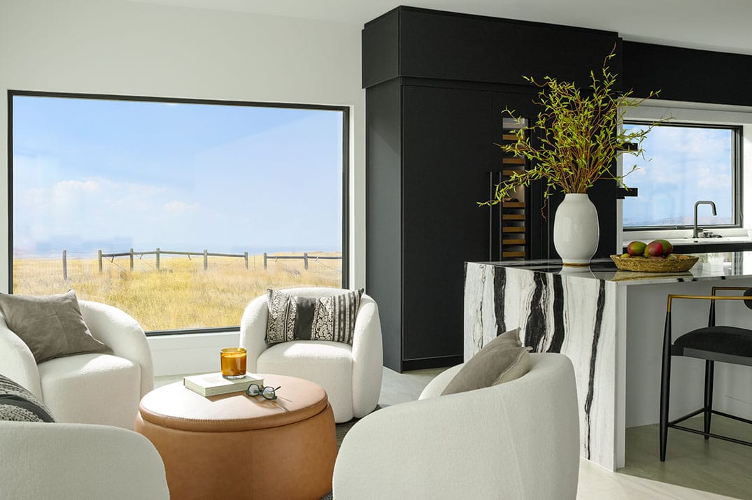 A bright living room with large black-frame windows maximizing natural light for energy efficiency.