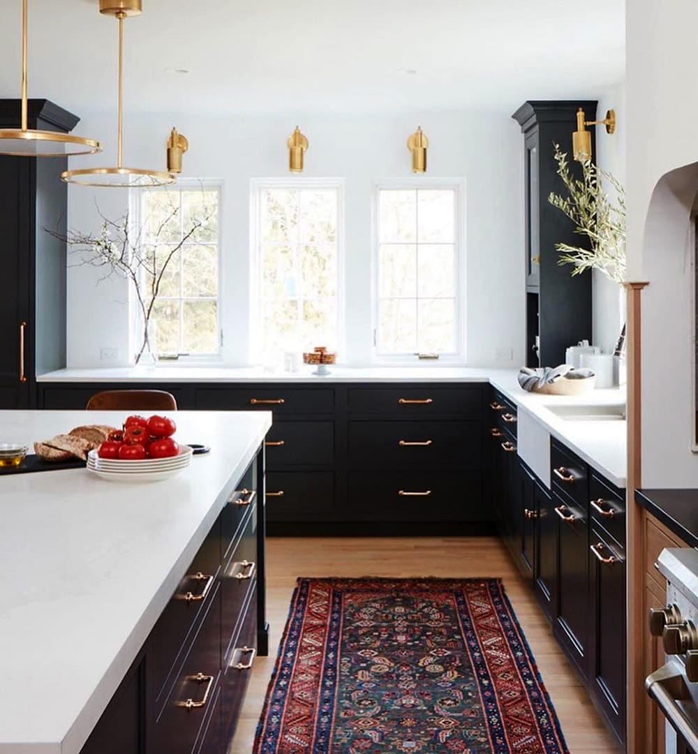 Three white casement windows sit between dark cabinets in traditional kitchen.