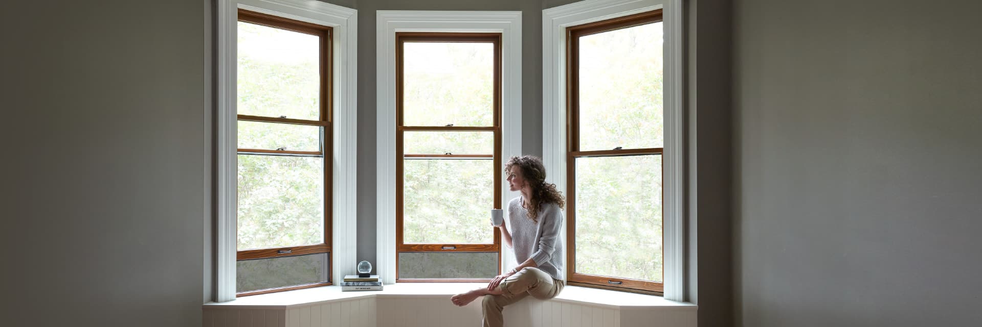 woman sitting on a window seat with three double-hung reserve windows surrounding her
