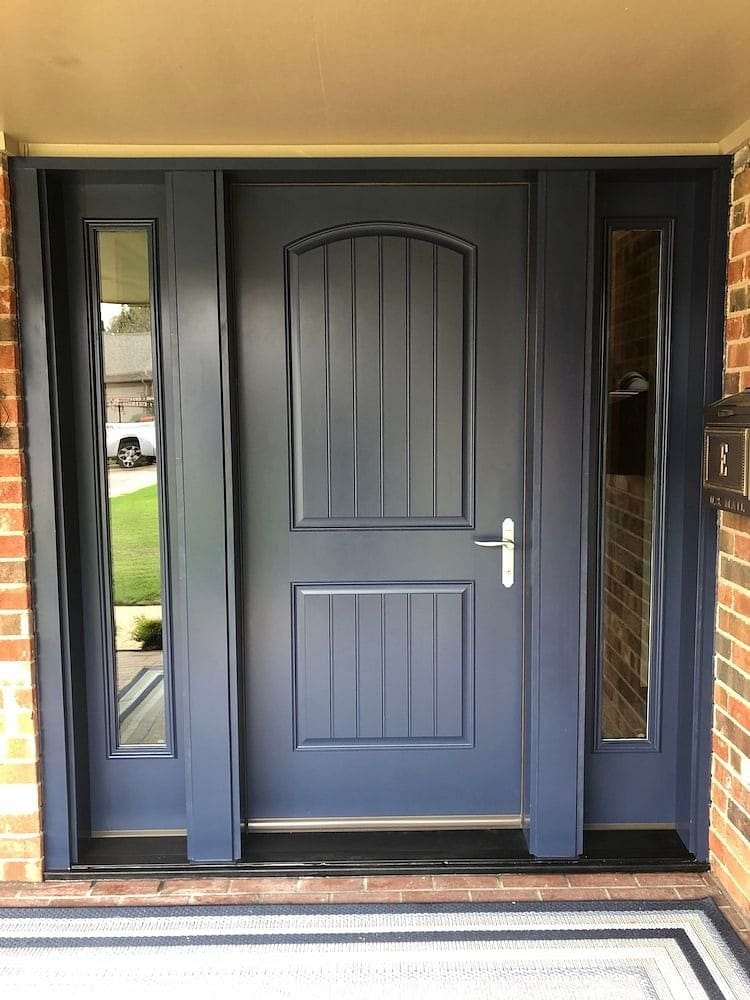 A blue front door is made of fiberglass and has two full light sidelights, one on each side.