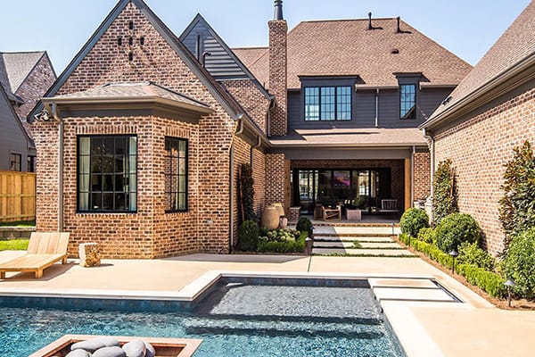 traditional brick home back deck swimming pool black casement windows