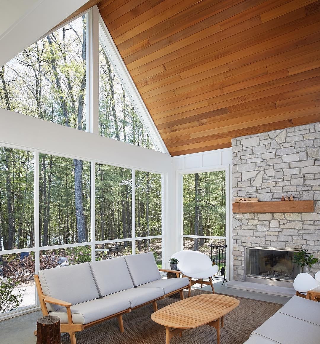 Window Wall Maximizes Light In Mid-Century Living Room mid-century living room looks out to wooded backyard through wall of windows with triangle windows near ceiling