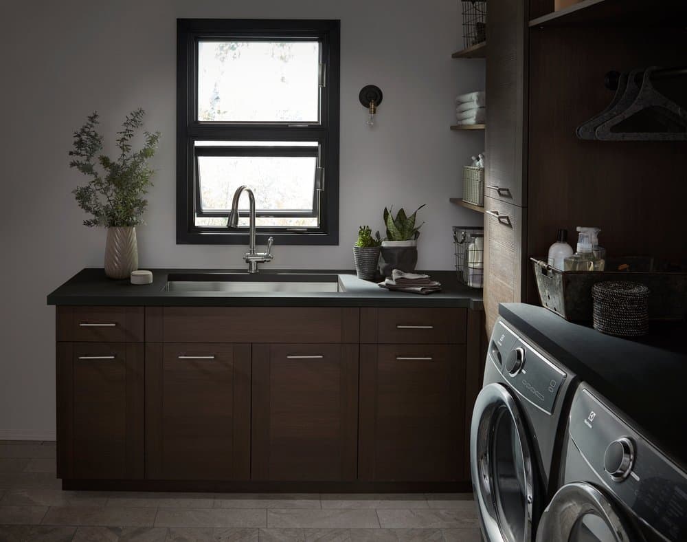 Stacked Awning Windows Make Stunning Design Statement Laundry room with dark wood cabinets, black stacked awning windows, and gray washer and dryer