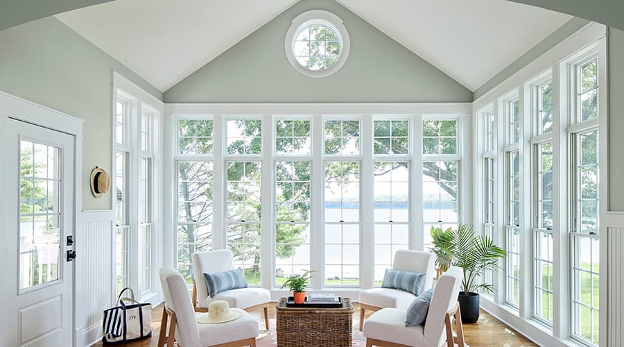 A bright white sunroom overlooks a beautiful lake view.