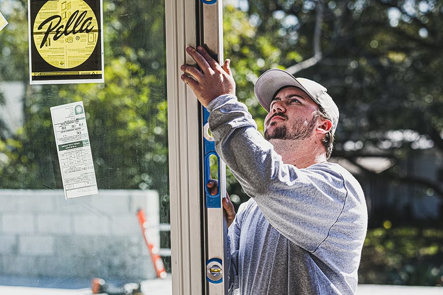 a contractor installing a new sliding glass door by using a level to ensure proper placement