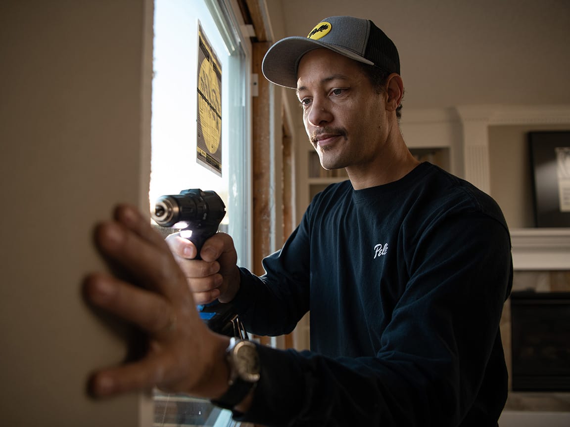 Technician installing a replacement window using power tools.
