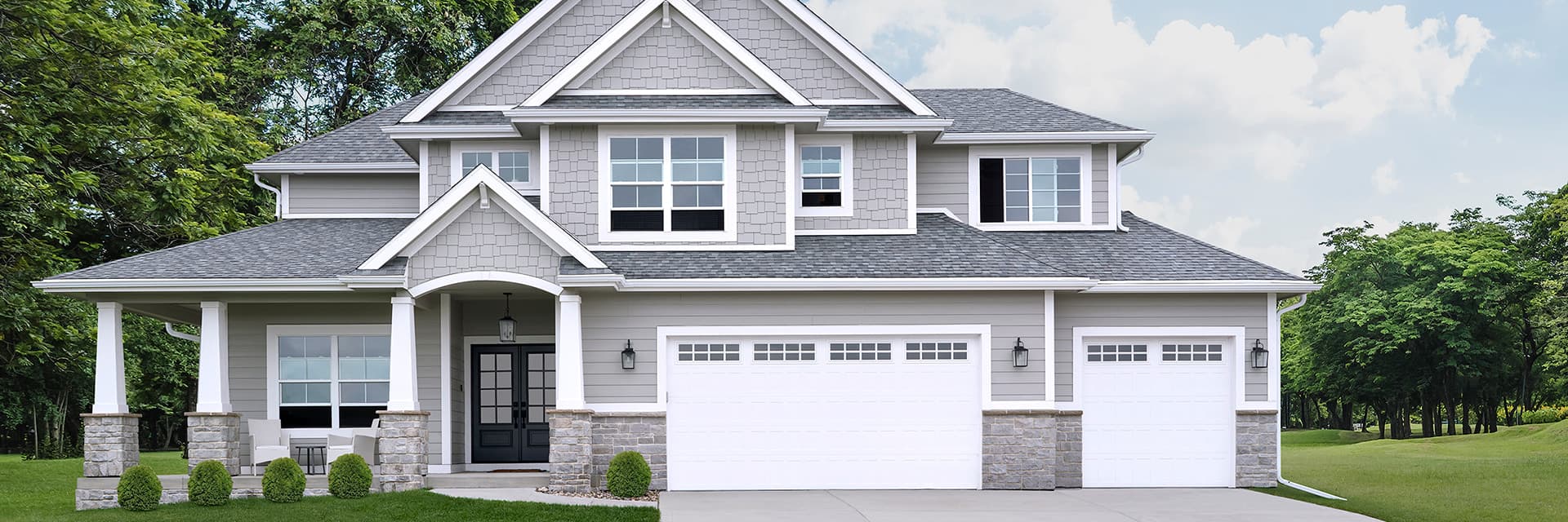 A large gray home with white windows and a white garage door.