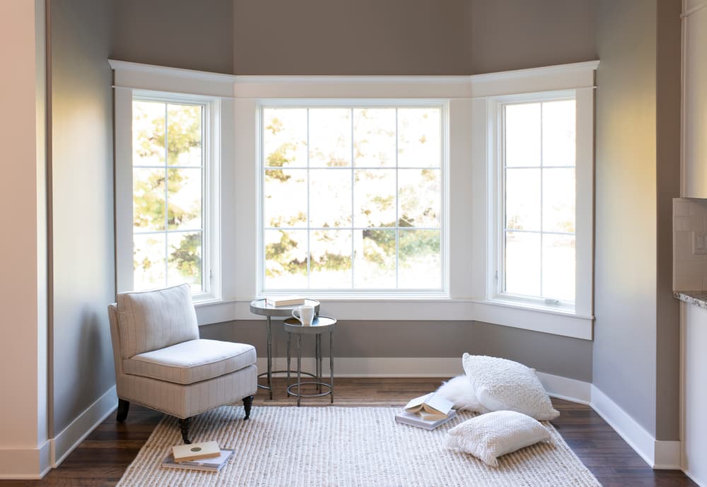 Bay Window Creates A Cozy Reading Nook Small reading nook with chair and large bow window with traditional grille pattern