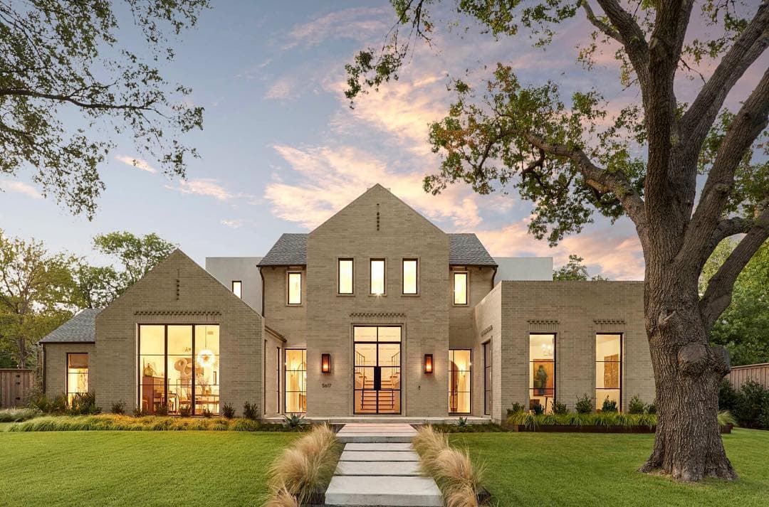 Large Windows Light Up Contemporary Home At Dusk tan modern home at dusk with large windows and doors lit up