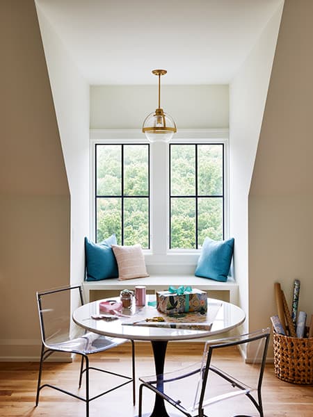 a home with a dormer window and window seat, which is decorated with three throw pillows