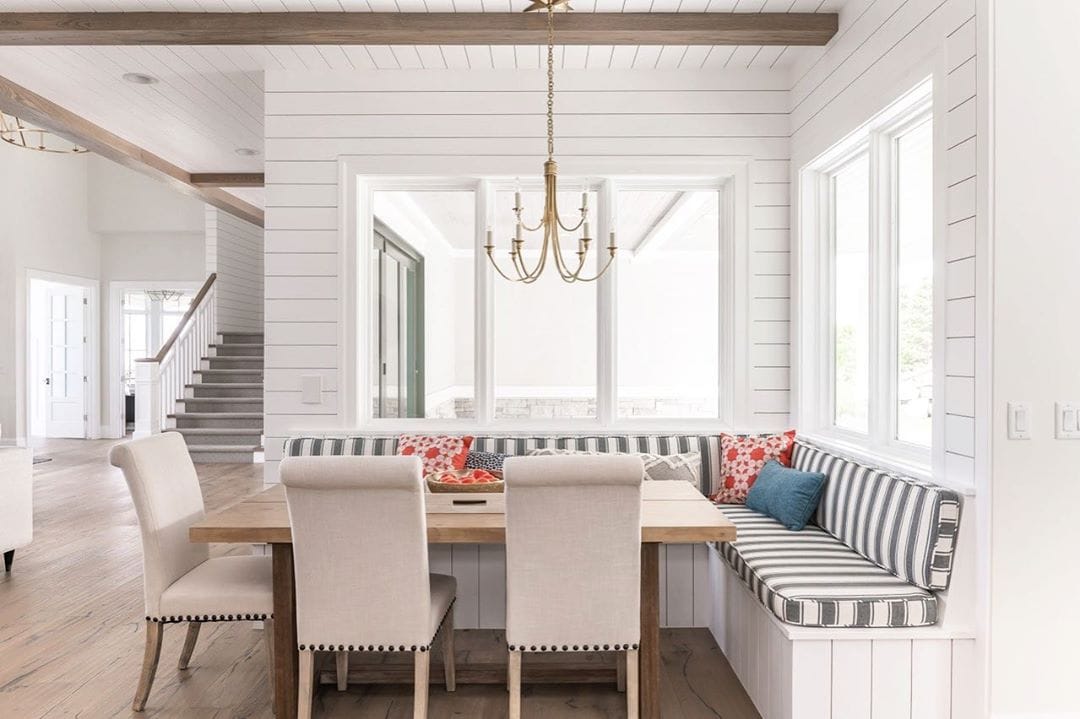 Picture Windows Illuminate Farmhouse Style Dining Nook corner dining nook surrounded by white picture windows
