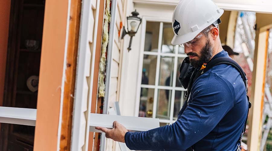 two home construction workers installing power by pella windows