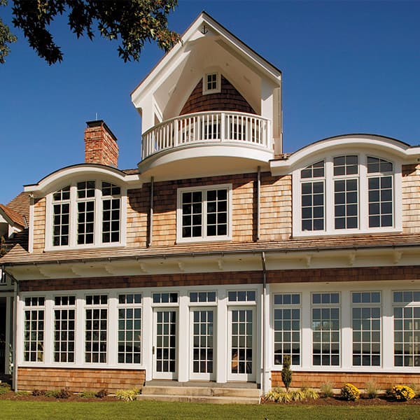 large home with wood siding and two sets of eyebrow dormer windows