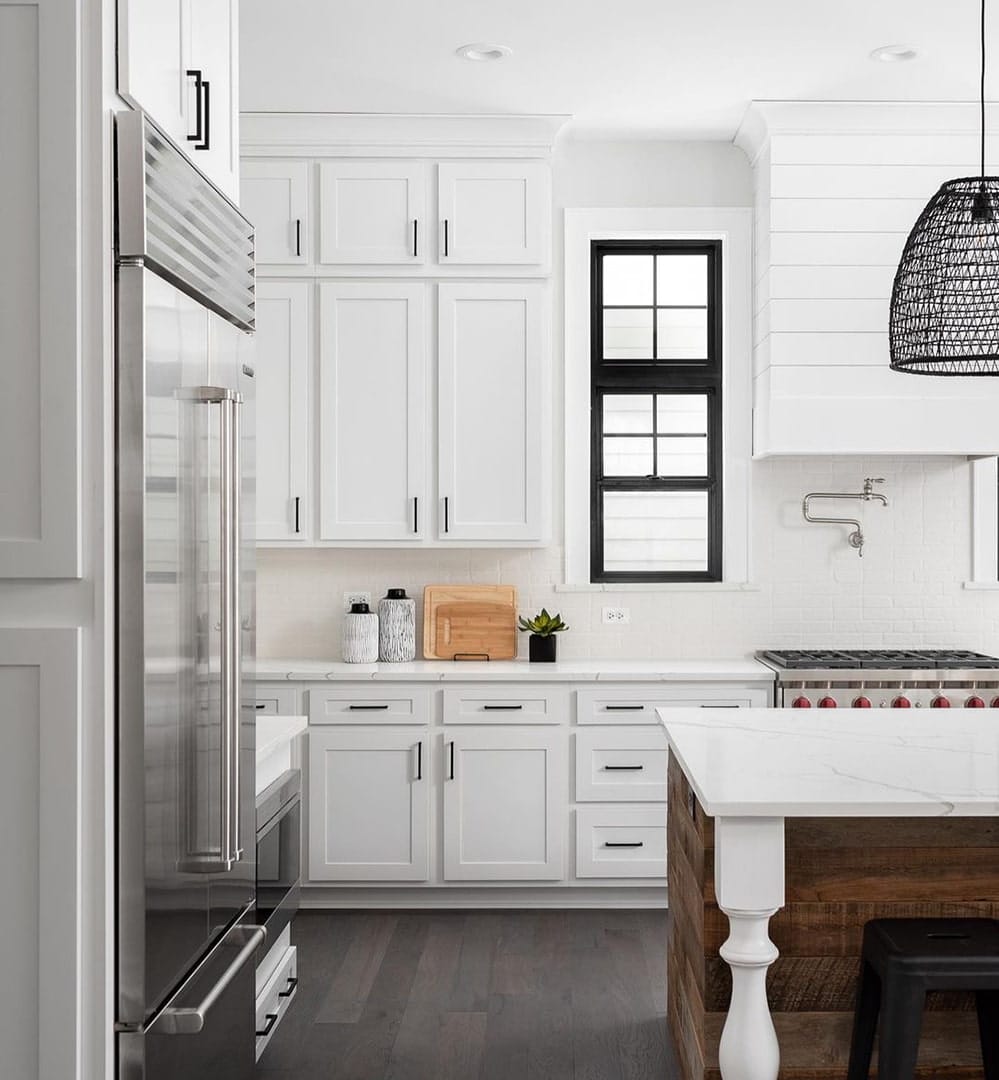 A white farmhouse kitchen has a black picture window stacked on a black double-hung window.