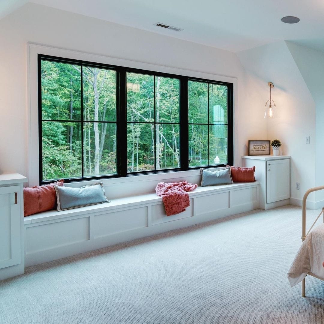 Three black windows with grilles create space for a bedroom window seat below.