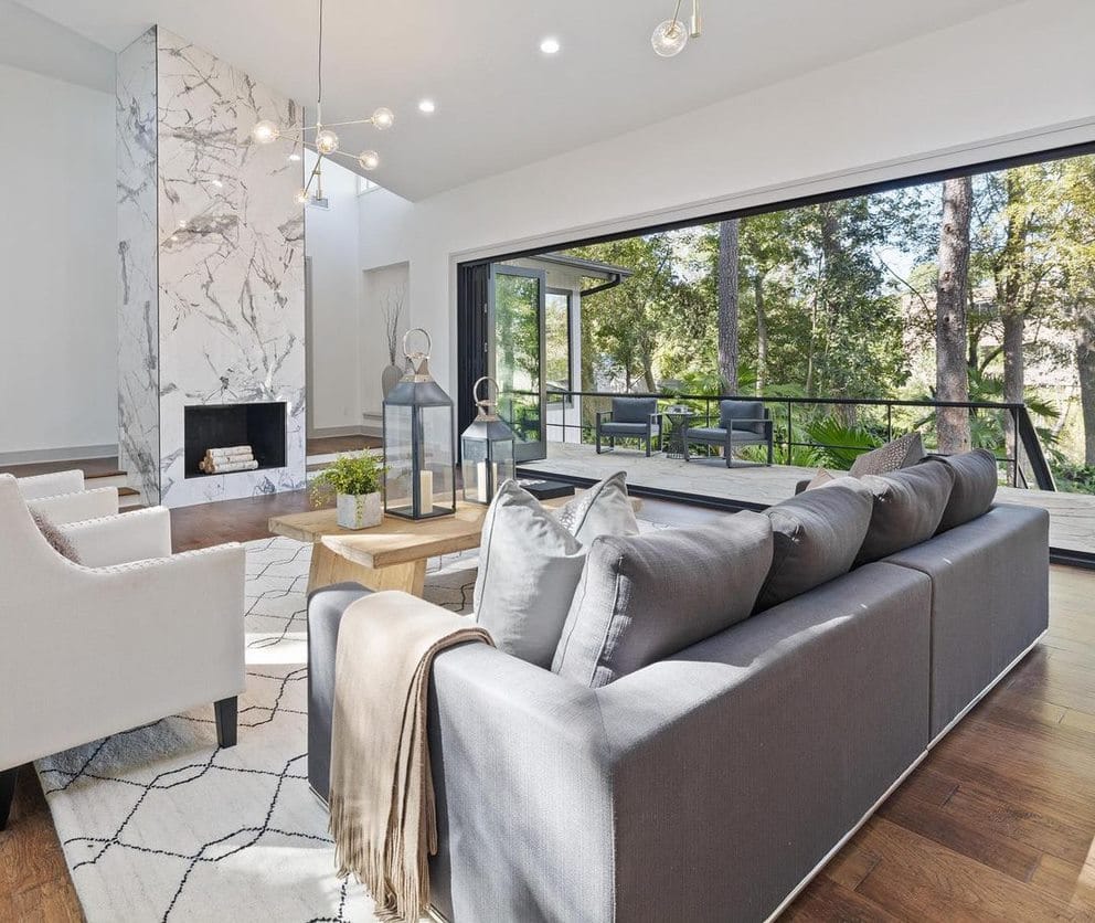 A modern living room features a black accordion glass door on the back wall, opening up to an outdoor deck.