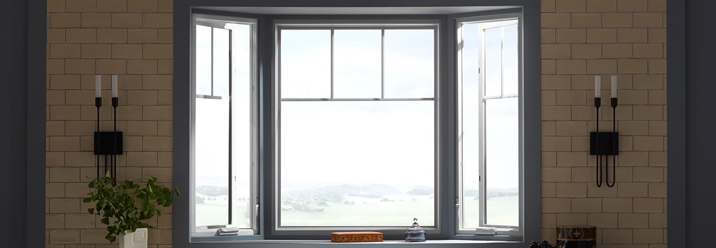 A brick kitchen wall surrounds a large gray bay window unit.