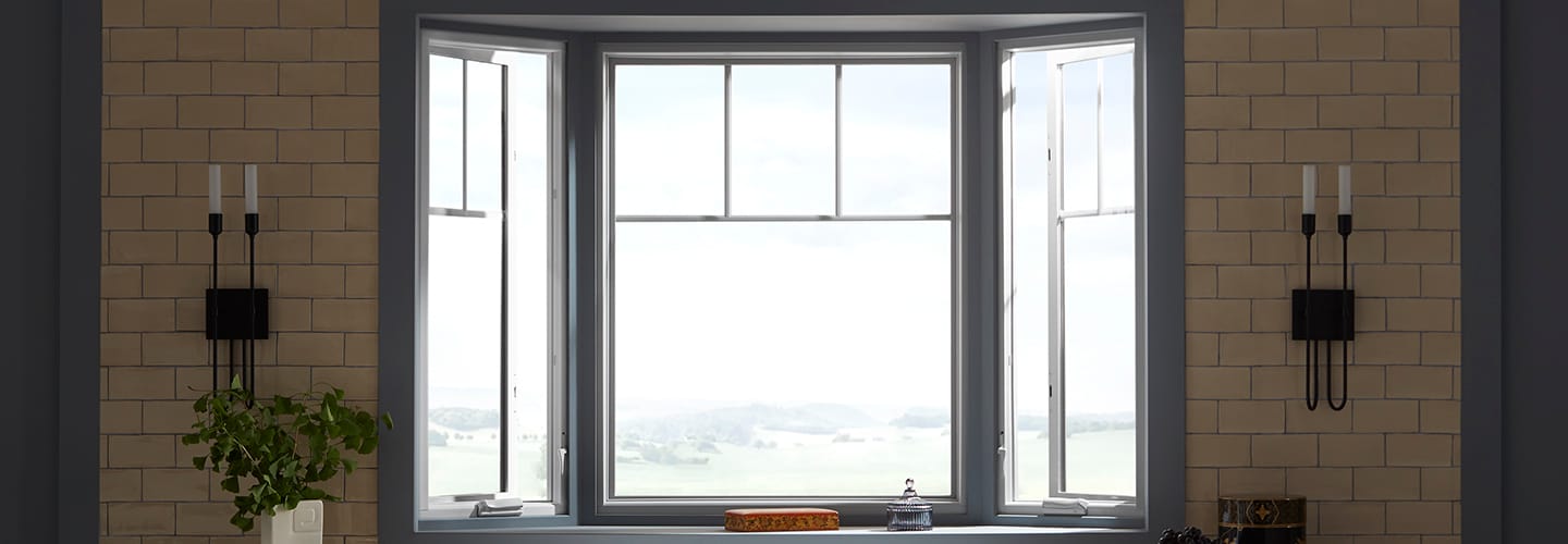 A brick kitchen wall surrounds a large gray bay window unit.