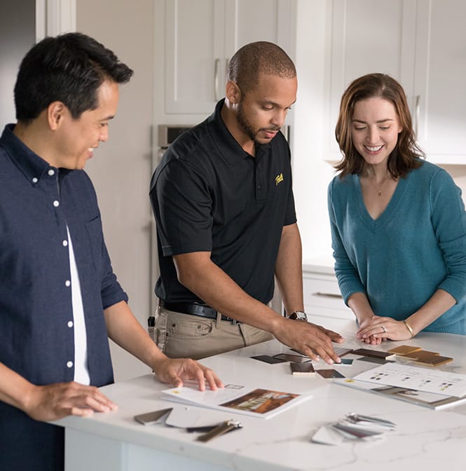 Three people reviewing design materials on a white countertop in a Philadelphia home.