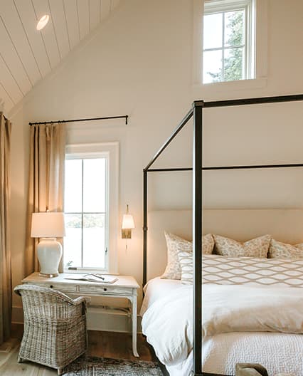 Elegant bedroom featuring a traditional window overlooking the outside from the upstairs.