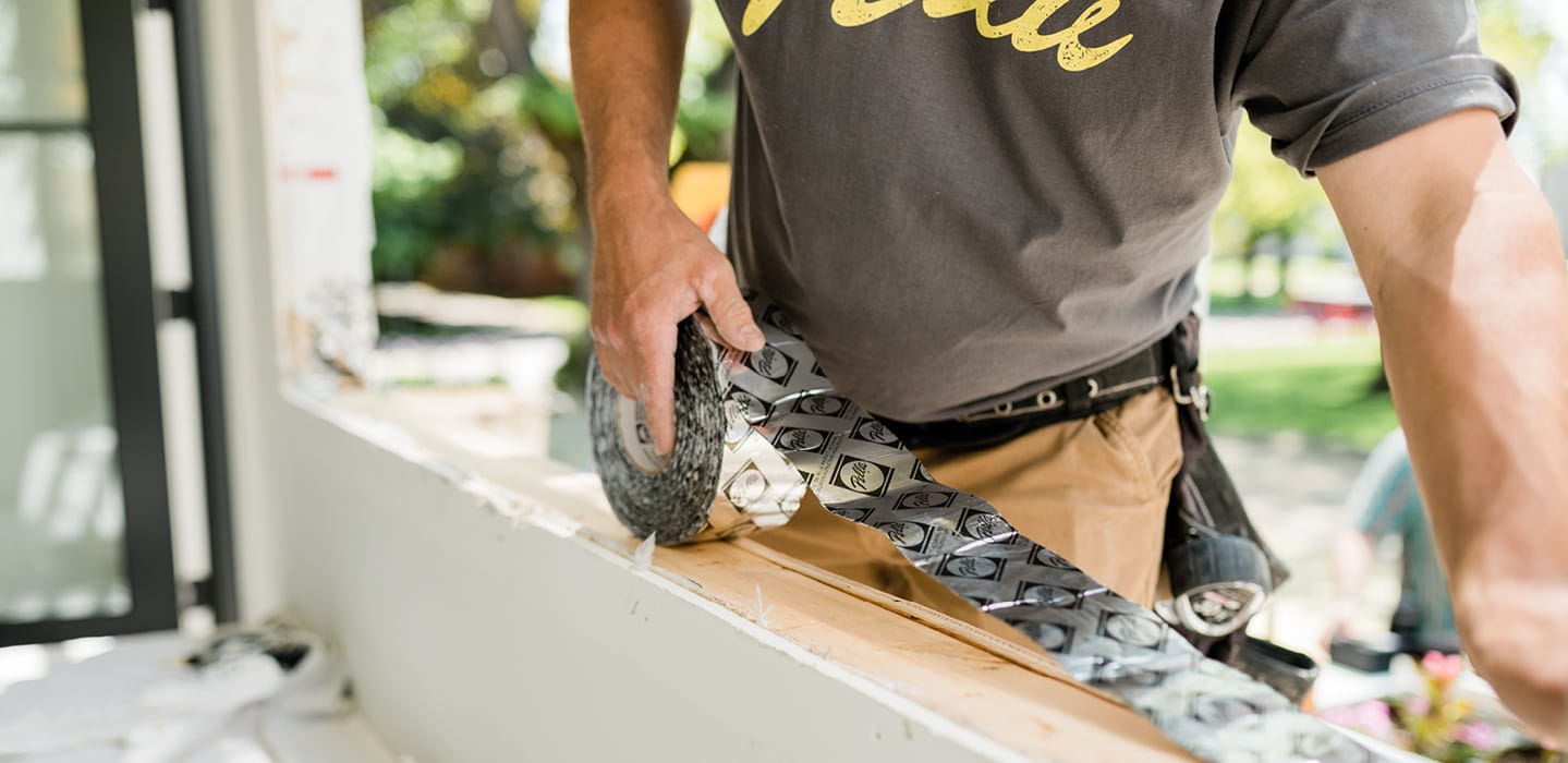 a construction worker using smartflash tape on a window installation project