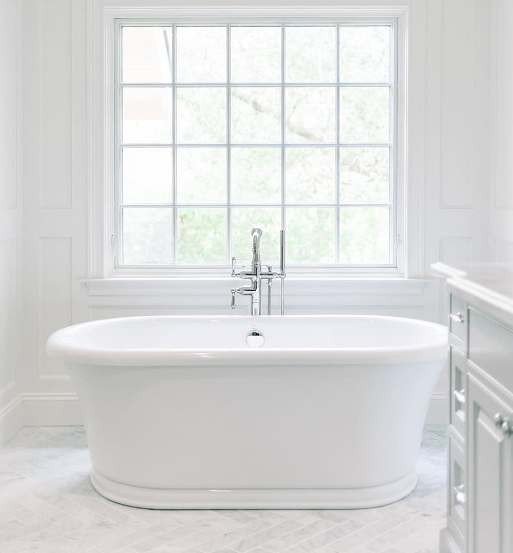 A traditional awning window with grilles over a white bathtub.