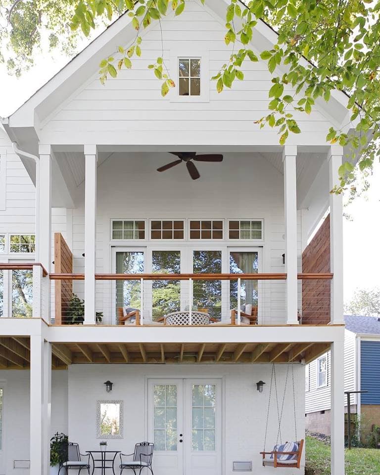 Custom Crafted Windows & Patio Doors Bring Light Into Home back of a white three story house with white sliding patio doors on the deck level and white french doors below