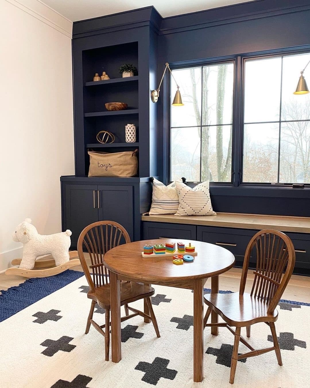 Black casement windows sit above a built-in window seat in a kids' playroom.