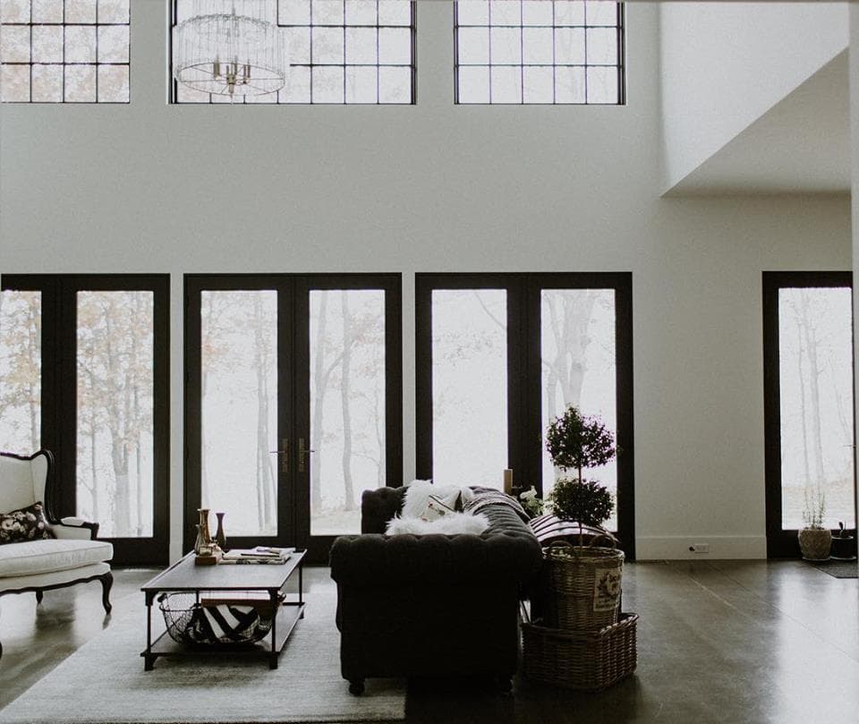 Wall of Black French Doors Are Centerpiece In Living Room open concept living room with high ceilings and a wall of three black french doors