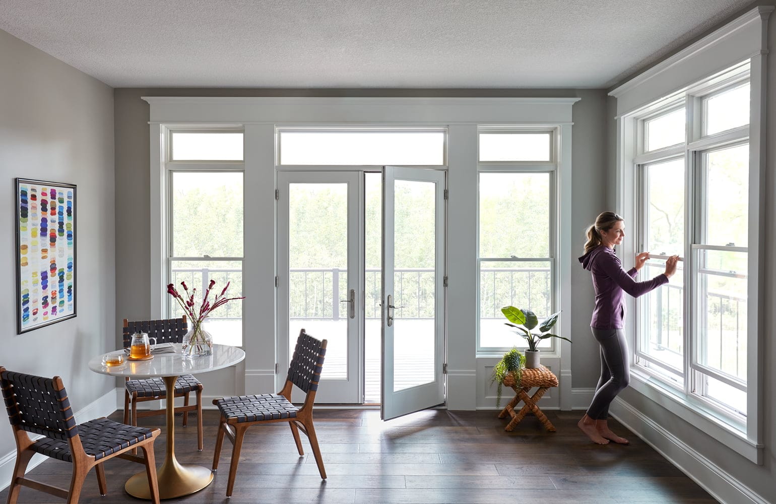 A four-season room with white windows and a hinged door making up three of the four walls.