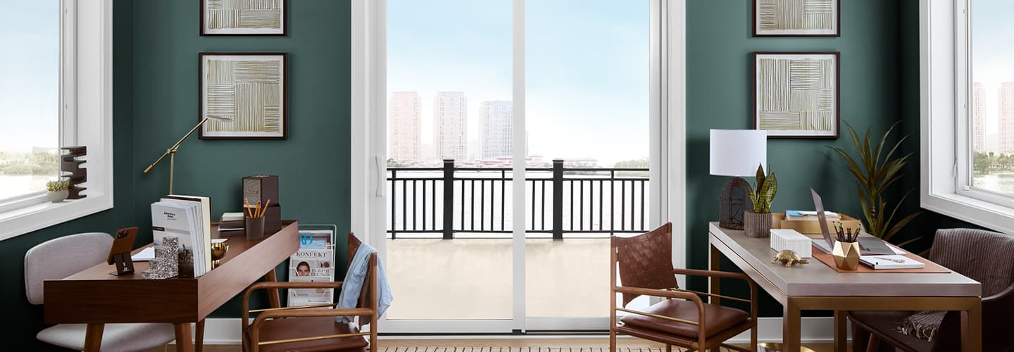 Green office space with white sliding door with a city view and two wood desks