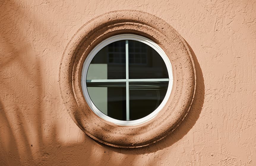 Round white trim window in a bathroom with a black grille