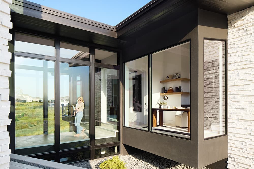A mom holding her baby is walking through an interior, glass-walled walkway.