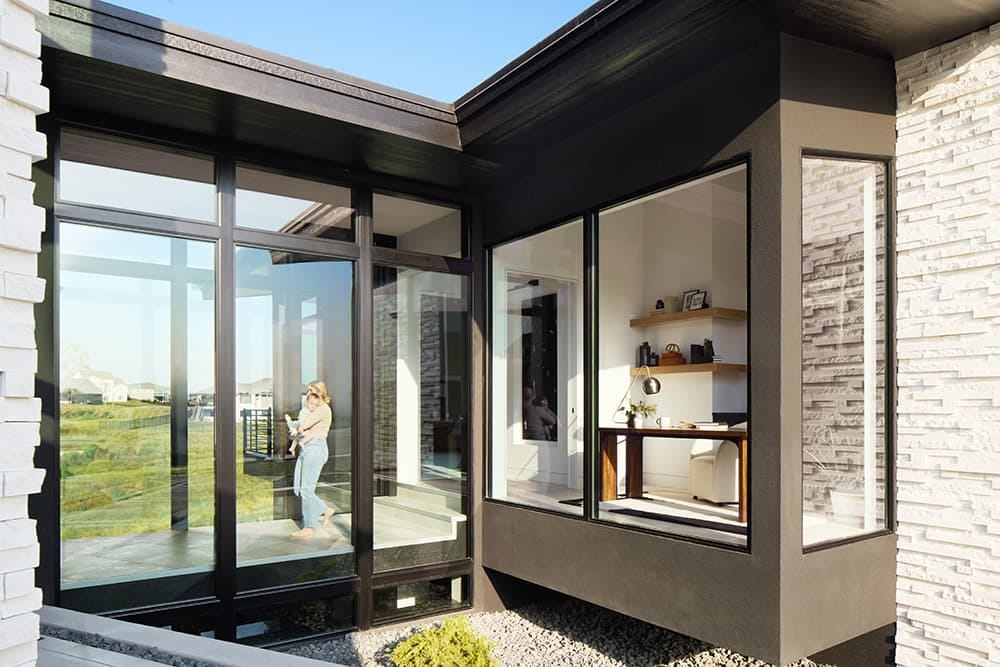 A mom holding her baby is walking through an interior, glass-walled walkway.