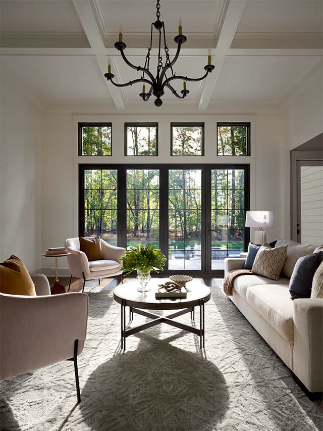 The view of a black four-panel patio door with grilles-between-the-glass on the far side of a long living room.