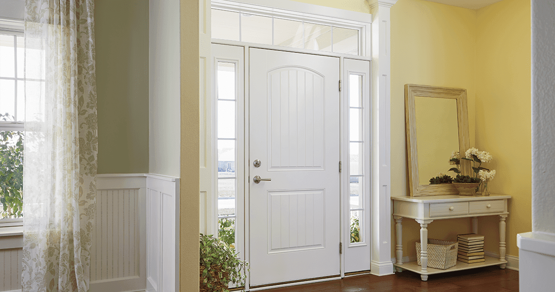 a bright entryway features a white front door with sidelights and transom