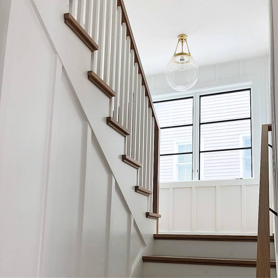 Custom Grille Pattern Brings Interest To Casement Windows white staircase landing with two black casement windows with horizontal grille patterns