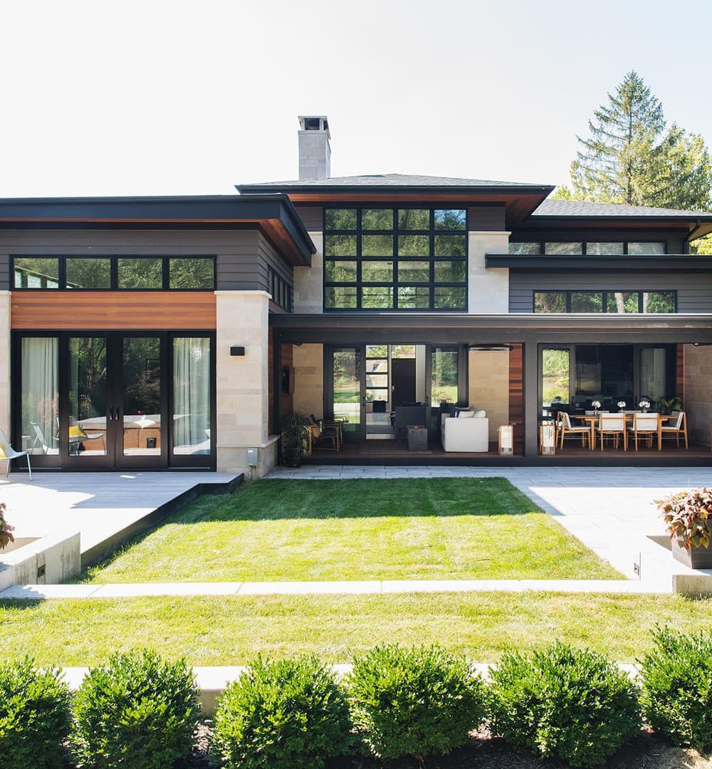 Modern and contemporary home features sliding patio doors and picture windows creating walls of glass across the back of the house.