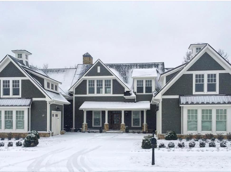 White Windows Complement Gray Farmhouse Exterior Gray farmhouse with white double-hung windows covered in snow