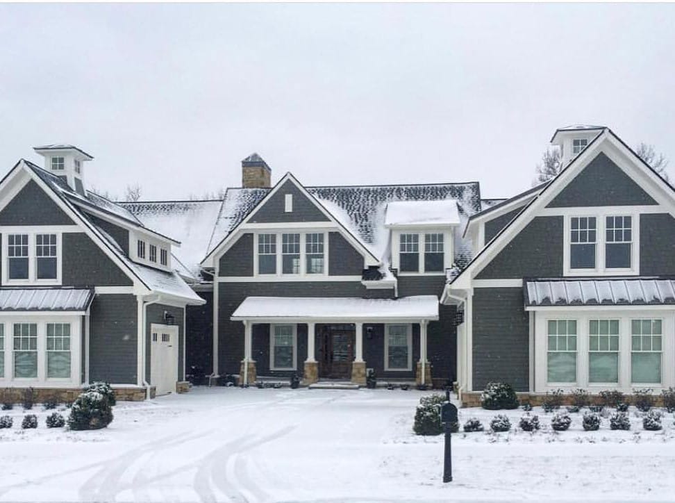 White Windows Complement Gray Farmhouse Exterior Gray farmhouse with white double-hung windows covered in snow