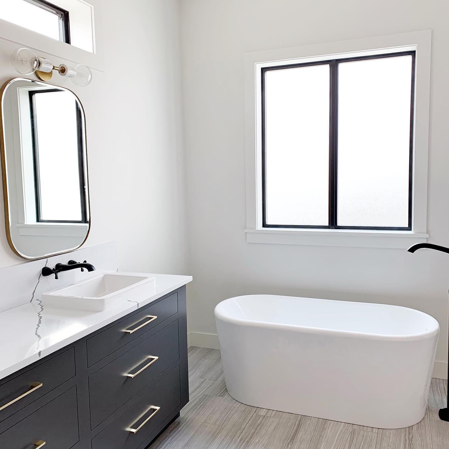 Sliding Window Invites Fresh Air Into Modern Bathroom Black and white bathroom features white tub with black sliding window overhead