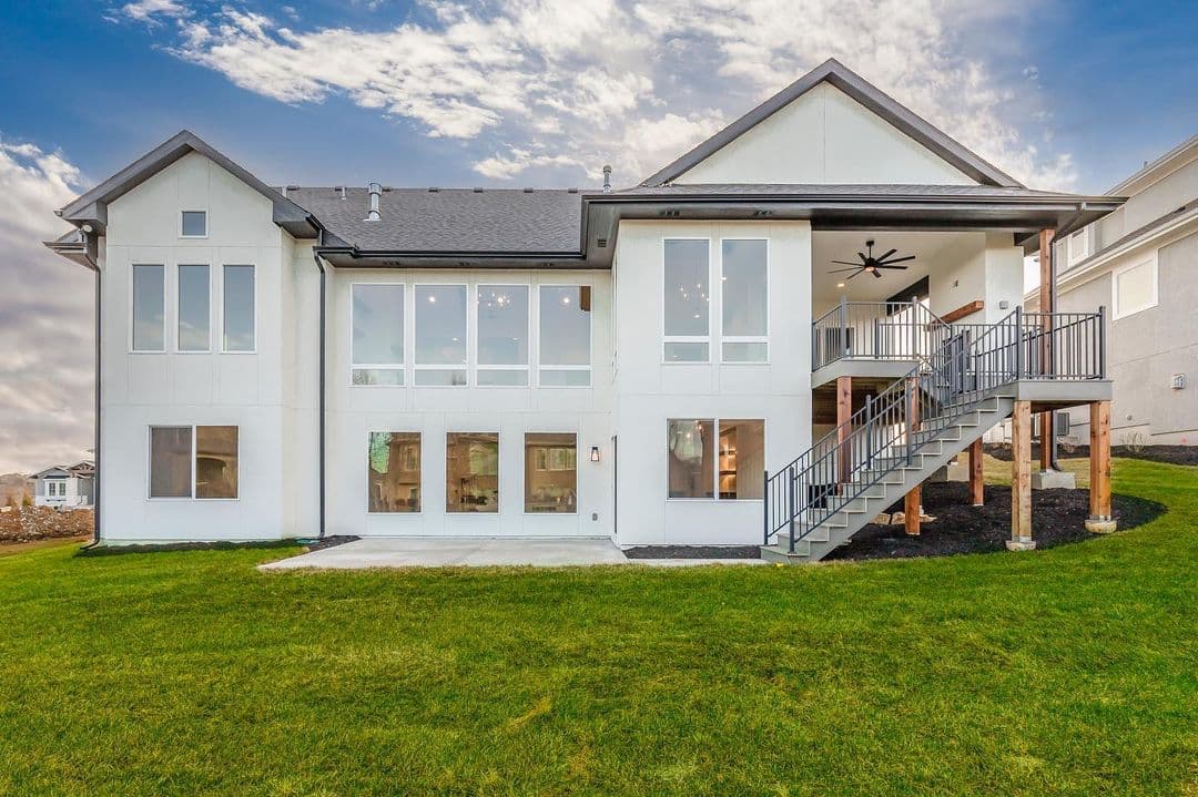 The back of a white home features numerous white picture windows, including those in the basement.