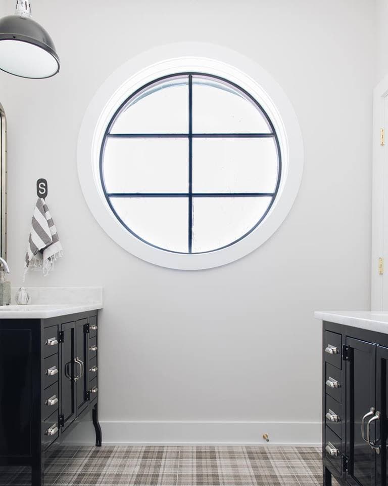 Black & White Circle Window In Contemporary Bathroom white bathroom with black vanities on either side and a large circle window in the middle