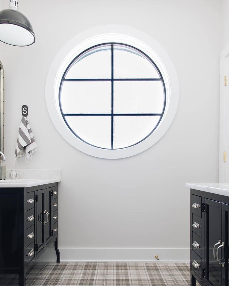 Black & White Circle Window In Contemporary Bathroom white bathroom with black vanities on either side and a large circle window in the middle