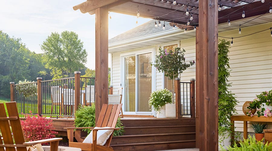 Backyard deck with wooden pergola, seating area, and sliding glass door.